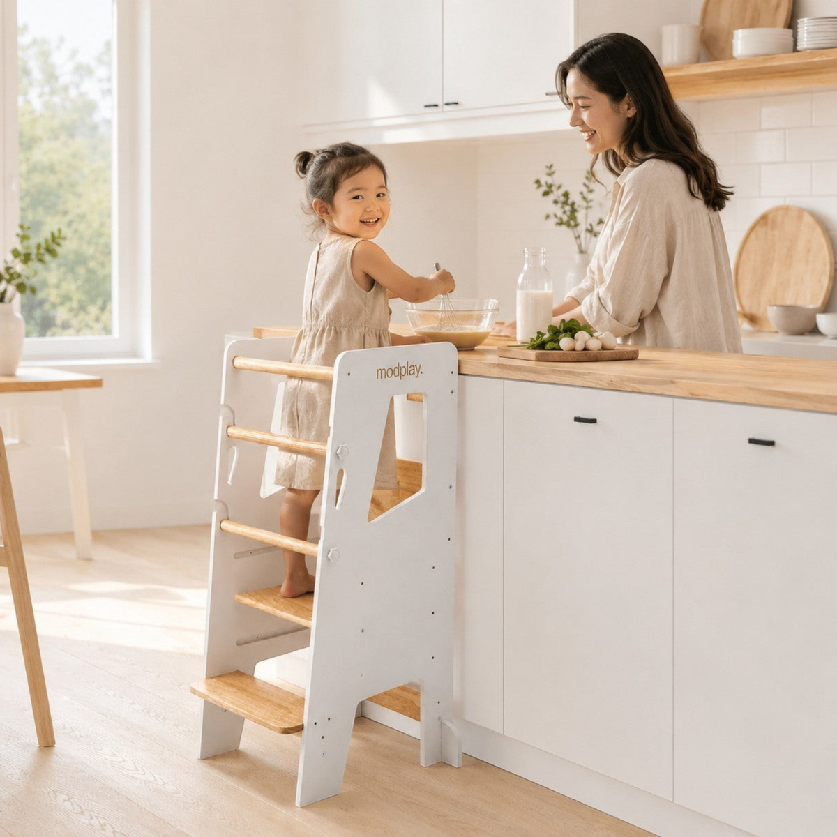 modplay Montessori learning tower in white and natural wood, used by a child in a bright modern kitchen