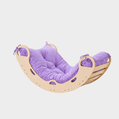 modplay Montessori rocker made of natural wood with a soft purple cushion for climbing, rocking, and resting.