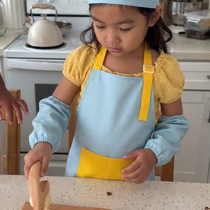 modplay Montessori wooden kitchen tool set with a child in a chef hat and apron cutting fruit on a wooden board